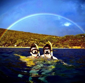 a couple smiling under a rainbow over Hanauma Bay