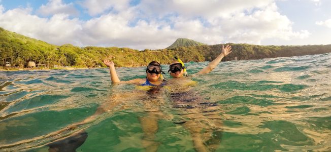 couple snorkeling at Hanauma Bay with Koko head in the background