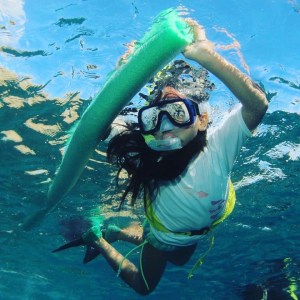 a girl snorkeling in Hawaii while holding a pool noodle